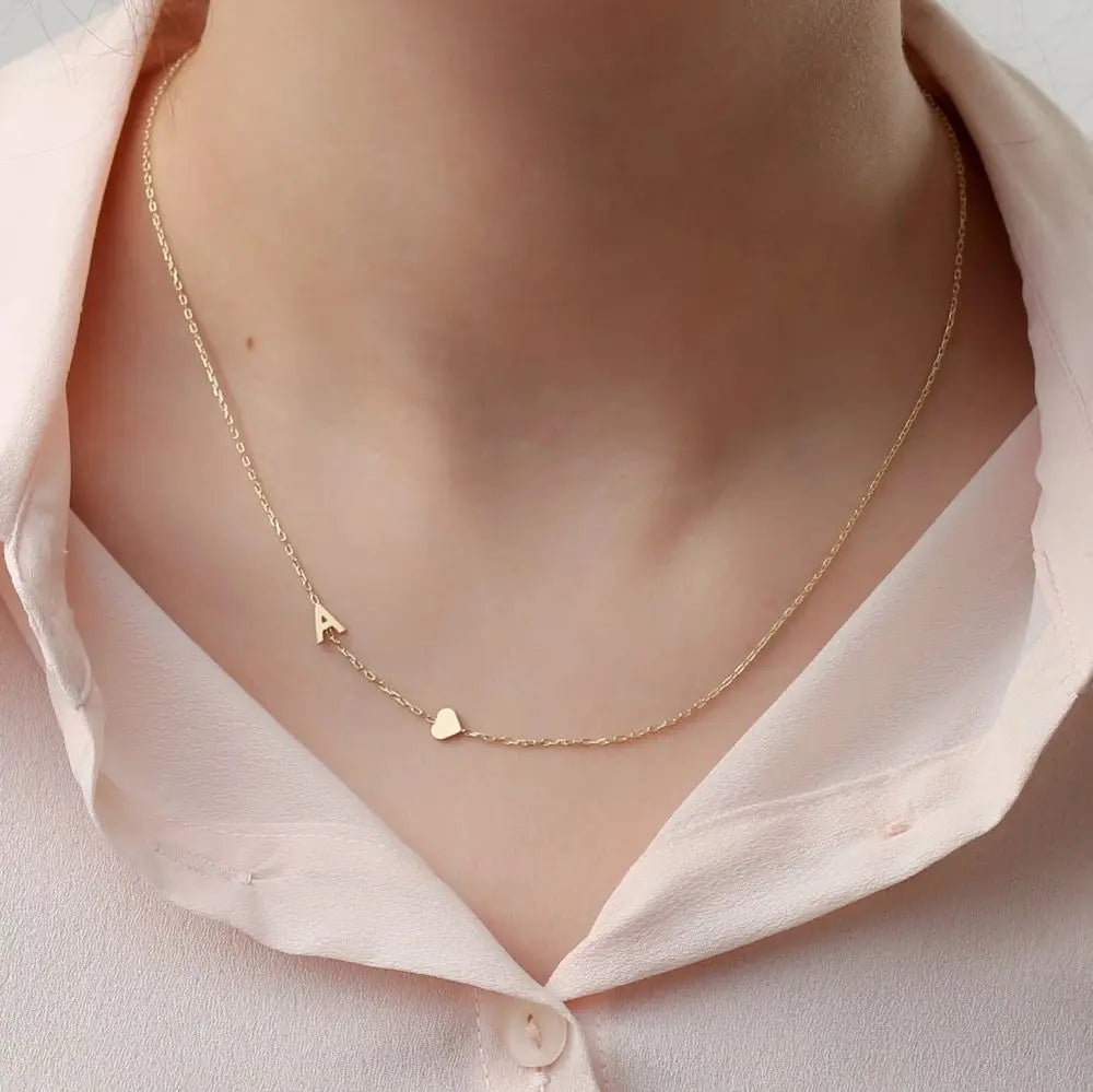 Collar personalizado con iniciales, de la marca Auxana, con cadena delicada y letras grabadas en plata.