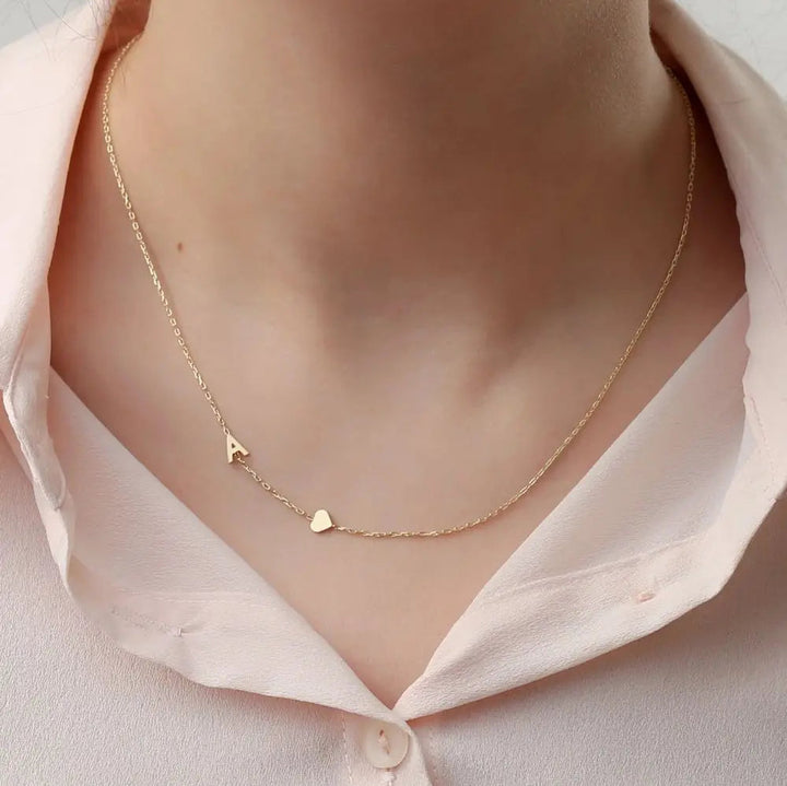 Collar personalizado con iniciales, de la marca Auxana, con cadena delicada y letras grabadas en plata.
