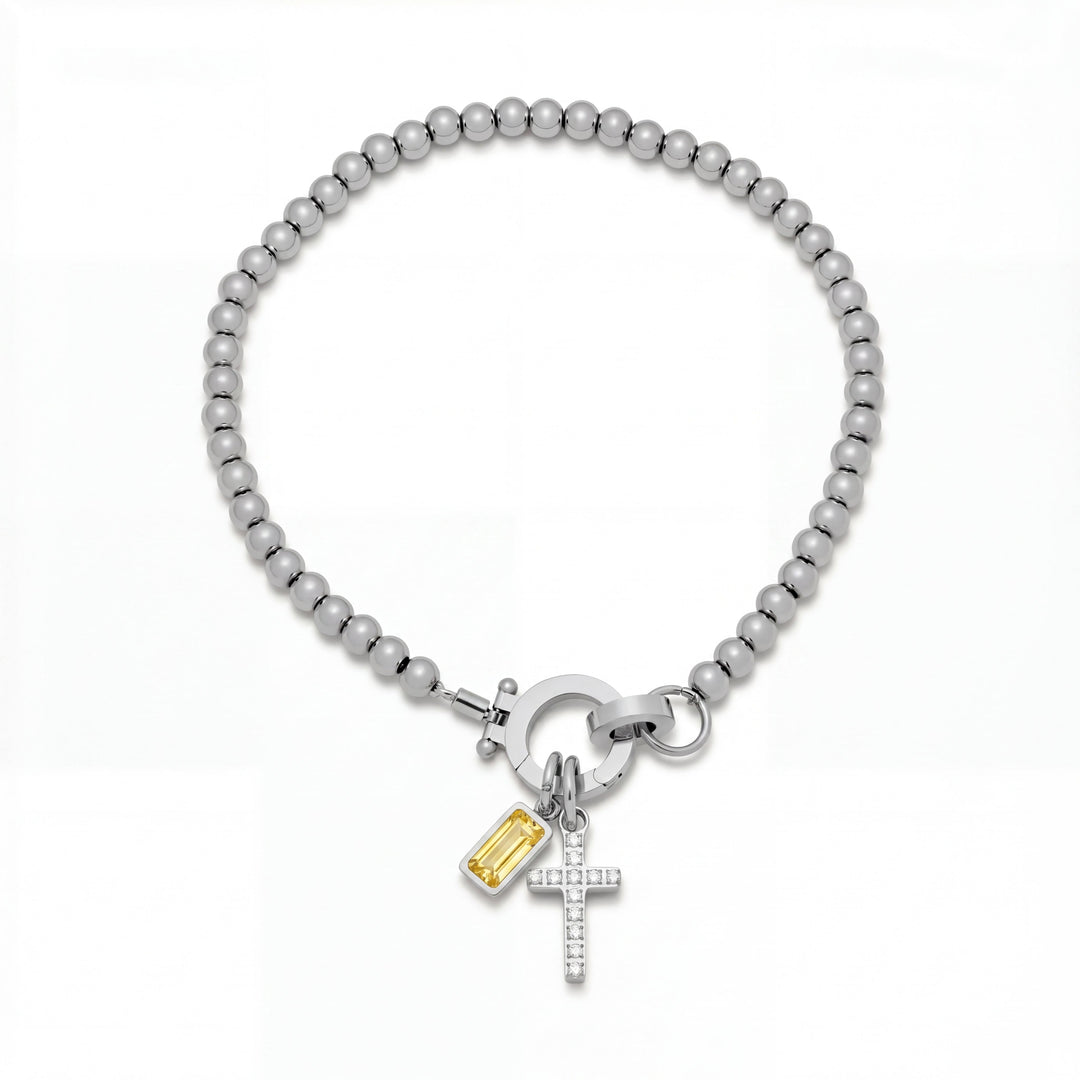 Pulsera Auxana con dije de cruz y piedra natal en joyería de plata, con detalles elegantes y estilo sofisticado.