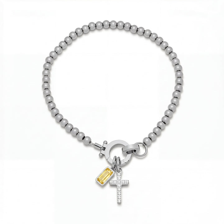 Pulsera Auxana con dije de cruz y piedra natal en joyería de plata, con detalles elegantes y estilo sofisticado.