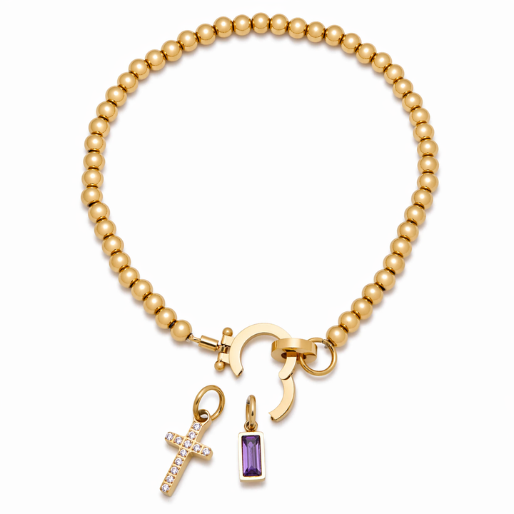 Pulsera de Auxana con dije de cruz y piedra natal, joya elegante con detalles religiosos y piedra preciosa en la pieza.
