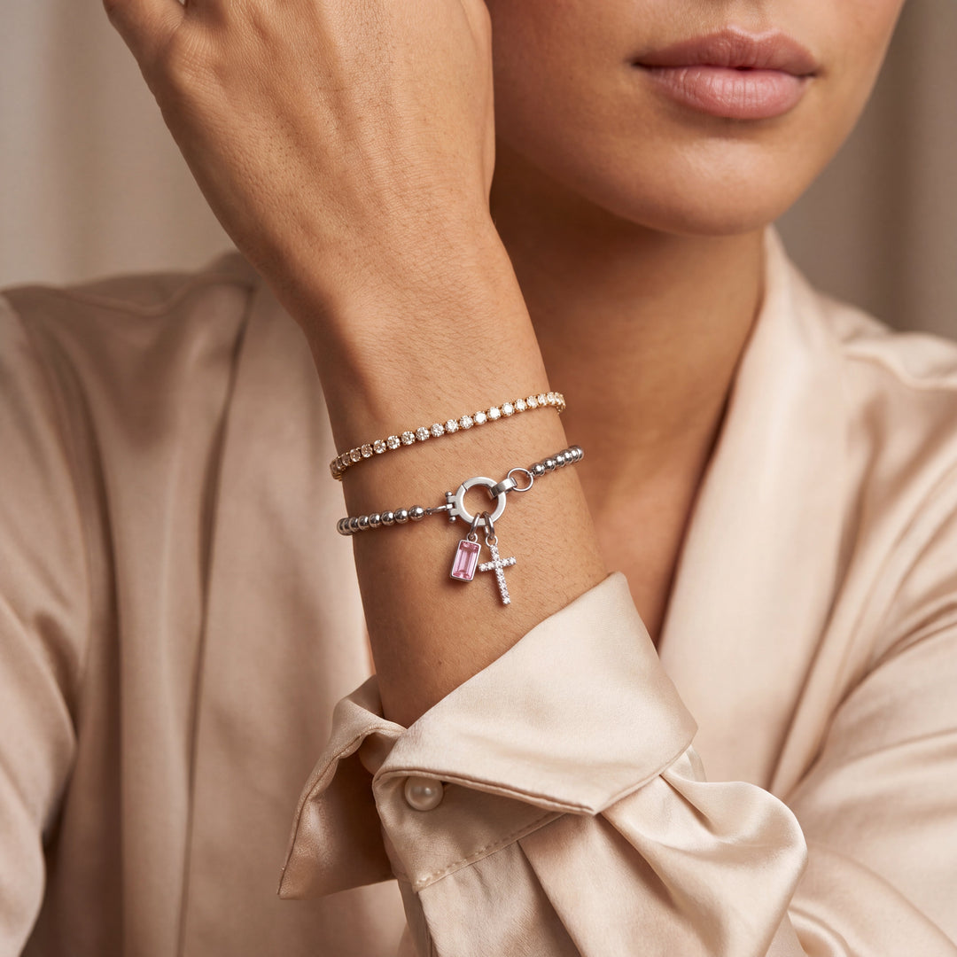 Pulsera de Auxana con dije de cruz y piedra natal, muestra la cadena y el colgante en detalle sobre fondo neutro.